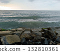 View of the Black Sea in Batumi, surrounded by large rocks, waves crashing against the rocks on the shore. 132810361