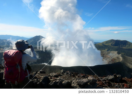 A female climber takes a photo of the smoke near the crater of Mount Aso A female climber takes a photo of the smoke near the crater of Mount Aso 132810450