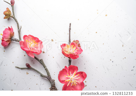 春日背景，盛開的紅梅花點綴在白色和紙上，並飾以金箔。 132811233