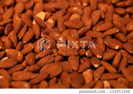 Delicious roasted almonds with spices are sold in large quantities at a vegetable market. Close-up. Almond background. 132811348