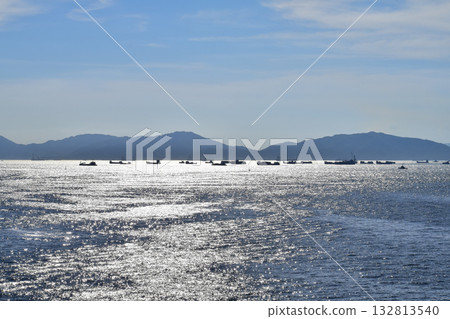 The view of the sea in the sunny day with blue sky and mountain and ships in the background. Calm sea and water. Sea background, wave pattern. Nature concept. 132813540