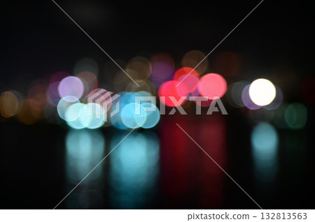 Bokeh effect of the light of skyscrapers from the seaside at night. Colorful and bright lights at night in the city. Nature and city scene. 132813563