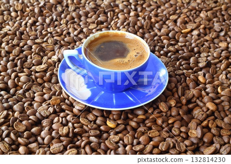 Close-up and top view of hot black coffee in blue coffee cup and roasted Thai coffee beans Close-up and top view of hot black coffee in blue coffee cup and roasted Thai coffee beans 132814230