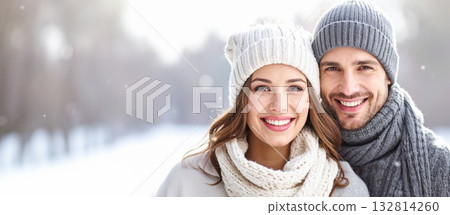 Happy smiling couple warming in winter clothes against blurred snowy background with falling snow 132814260
