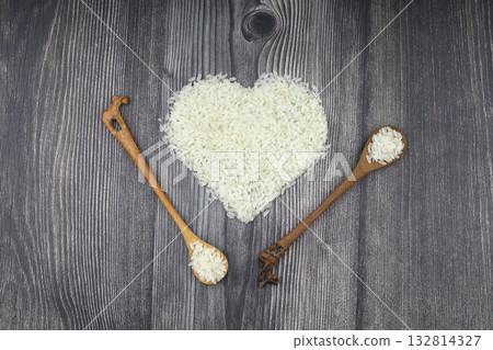 Heart-shaped rice on dark background. Love and valentines day concept. Raw long white rice in shape of heart. Traditional Asian food. Heart-shaped rice on dark background. Love and valentines day concept. Raw long white rice in shape of heart. Traditional Asian food. 132814327