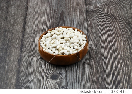 white kidney bean in wooden bowl isolated on wooden background. Top view. Flat lay white kidney bean in wooden bowl isolated on wooden background. Top view. Flat lay 132814331