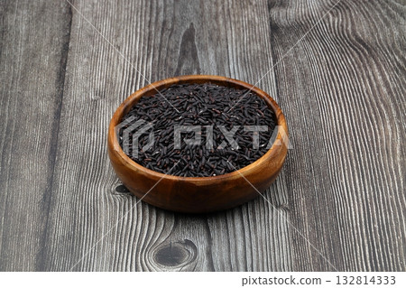 pile of black rice in a wooden bowl on a wooden table close-up pile of black rice in a wooden bowl on a wooden table close-up 132814333