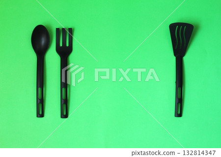 black fork and spoon on green background. 132814347