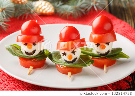 Delicious Snowmen made of mozzarella, tomatoes and basil on skewers close-up on a plate. Horizontal 132814738