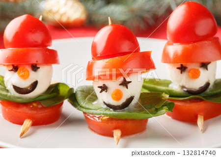 Close-up of Caprese salad on snowman-shaped skewers on a plate. Christmas food idea. Horizontal Close-up of Caprese salad on snowman-shaped skewers on a plate. Christmas food idea. Horizontal 132814740