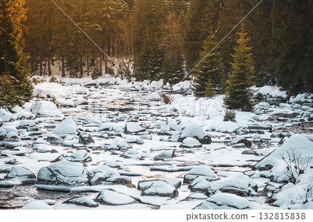 A peaceful winter evening at Jizera River, where snow blankets smooth rocks and trees. The serene atmosphere reflects the beauty of nature along the border of Czechia and Poland. A peaceful winter evening at Jizera River, where snow blankets smooth rocks and trees. The serene atmosphere reflects the beauty of nature along the border of Czechia and Poland. 132815838