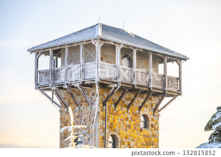 The lookout tower on Wysoki Kamien in the Jizera Mountains offers stunning winter views. Snow covers the structure, highlighting its unique architecture against a clear sky. 132815852