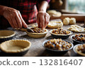 Baking mince pies scene, hands cutting dough and filling pastry tins with fruit mix 132816407