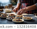 Baking mince pies scene, hands cutting dough and filling pastry tins with fruit mix 132816408