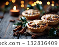 Christmas mince pies on a wooden table decorated with holly leaves and cinnamon sticks 132816409