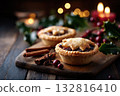 Christmas mince pies on a wooden table decorated with holly leaves and cinnamon sticks 132816410