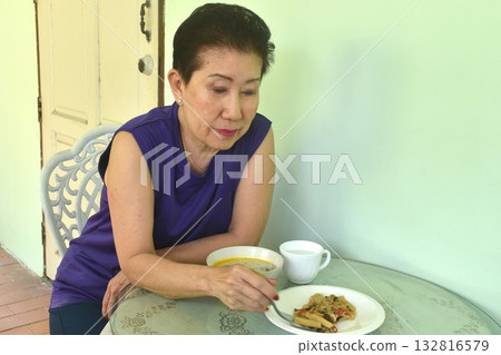 elder woman cooking and eating breakfast in home on morning elder woman cooking and eating breakfast in home on morning 132816579