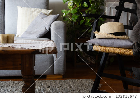 An illuminated living room interior with straw hat on chair,highlighting comfort and relaxed home decor 132816678