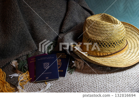 Several passports and stylish straw hat resting on a cozy knit blanket. Copy space 132816694
