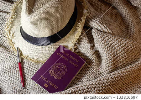 Italian passport, straw hat, pen for travel preparation.Travel concept. Copy space Italian passport, straw hat, pen for travel preparation.Travel concept. Copy space 132816697