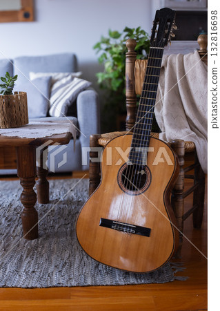 Acoustic guitar leaning on chair in cozy rustic living room. Vertical real picture 132816698