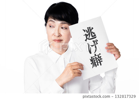 一位身穿白襯衫、表情不悅的老婦人，手裡拿著一張寫著「逃避習慣」的紙條。 132817329