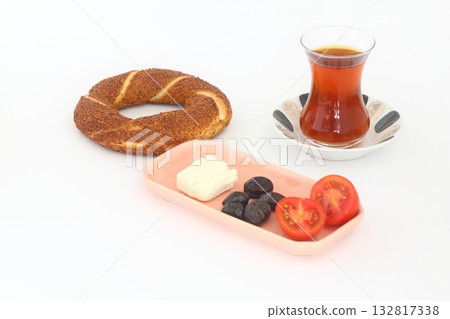 Turkish bagel, simit, tomatoes & Turkish tea on white background. Turkish bagel, simit, tomatoes & Turkish tea on white background. 132817338