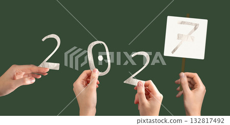 Hand holding metallic 2027 number in festive celebration. Shiny foil typography design symbolizing 132817492