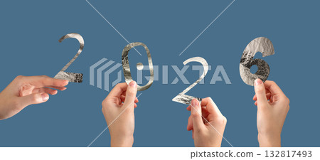 Hand holding silver metallic 2026 number in festive New Year celebration. Shiny textured foil Hand holding silver metallic 2026 number in festive New Year celebration. Shiny textured foil 132817493