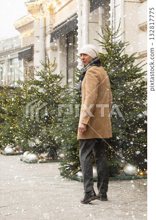 Adult caucasian man going to luxury store for shopping. Xmas holiday. Wearing warm clothing. Festive street with Christmas decorations. Adult caucasian man going to luxury store for shopping. Xmas holiday. Wearing warm clothing. Festive street with Christmas decorations. 132817775