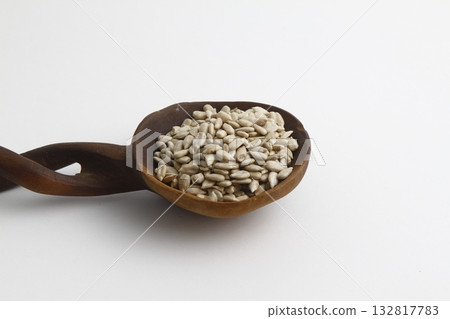 Full spoon of sunflower seed on a wooden board. Wooden spoon on a white background. Full spoon of sunflower seed on a wooden board. Wooden spoon on a white background. 132817783