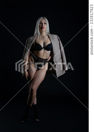Confident model poses in dark studio wearing stylish outfit and bold makeup 132817823