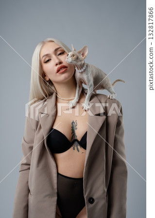 Stylish woman posing with a Sphynx cat in a studio setting Stylish woman posing with a Sphynx cat in a studio setting 132817866