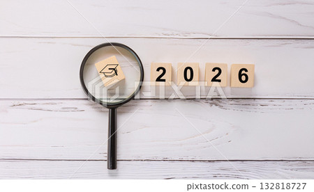 Black Graduation Cap Icon Under Magnifying Glass with Wooden 2026 Year Blocks 132818727