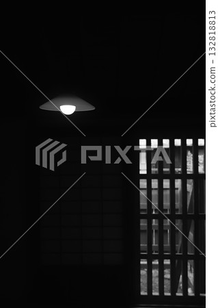 A Japanese house room with a small light in the shadows and a lattice window 132818813