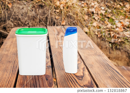 white container with a green lid and a shampoo bottle on a wooden background white container with a green lid and a shampoo bottle on a wooden background 132818867