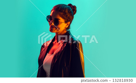 Confident woman smiling in dark sunglasses under turquoise and orange light 132818930