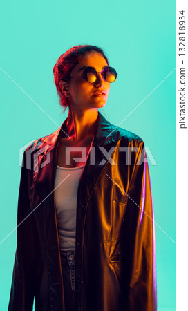 Elegant woman with round glasses posing under turquoise background light 132818934