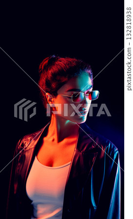 Woman in red and blue light wearing slim sunglasses and leather jacket Woman in red and blue light wearing slim sunglasses and leather jacket 132818938