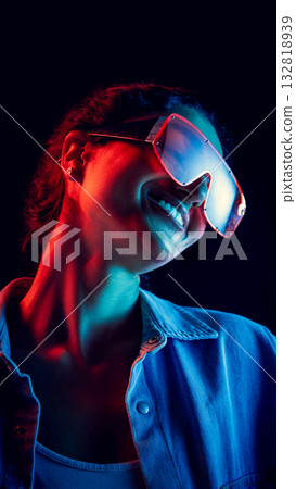 Smiling woman in oversized futuristic visor under red and blue neon light 132818939