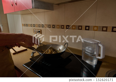 Father Cooking Stir-Fry In Warm Kitchen While Child Helps Prepare Dinner 132820171