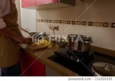 Adult Man Chops Potatoes While Child Helps In Modern Kitchen With Pot On Stove 132820185