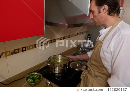 Father Cooking Soup in Modern Kitchen While Child Helps With Dinner 132820187
