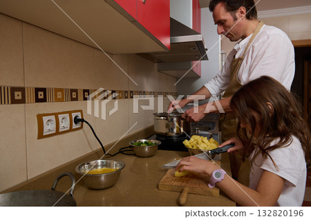 Father Cooking Soup With Daughter Helping in Kitchen During Family Dinner 132820196