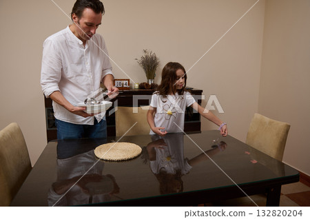 Father And Daughter Preparing Dinner At Home, Setting The Table Together Father And Daughter Preparing Dinner At Home, Setting The Table Together 132820204