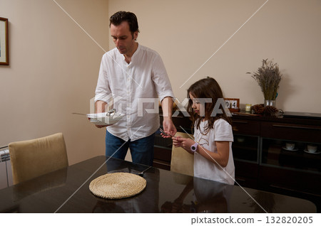 Father And Daughter Share Dinner Time: A Warm Family Moment Of Serving Plates At Home 132820205