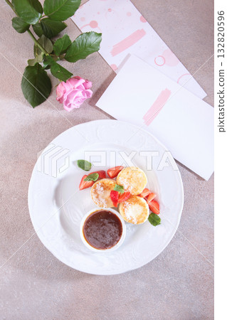 Cheesecakes with strawberries and jam. Healthy breakfast. A menu page and a rose on the table. View from above. Cheesecakes with strawberries and jam. Healthy breakfast. A menu page and a rose on the table. View from above. 132820596