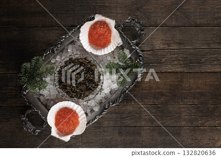 Black and red caviar on a silver-plated tray and on ice. Natural delicacy. Branch of spruce and ice on a tray. Natural omega. Flat lay. Top view. Copy space. Black and red caviar on a silver-plated tray and on ice. Natural delicacy. Branch of spruce and ice on a tray. Natural omega. Flat lay. Top view. Copy space. 132820636