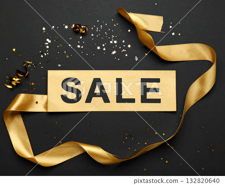 A bold Sale banner is draped across a plain black background with confetti and sparkles. A bold Sale banner is draped across a plain black background with confetti and sparkles. 132820640
