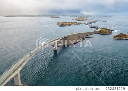Truck moving along the winding Atlantic Ocean Road over ocean waters, linking islands amid Norways stunning seascape. Truck moving along the winding Atlantic Ocean Road over ocean waters, linking islands amid Norways stunning seascape. 132821219